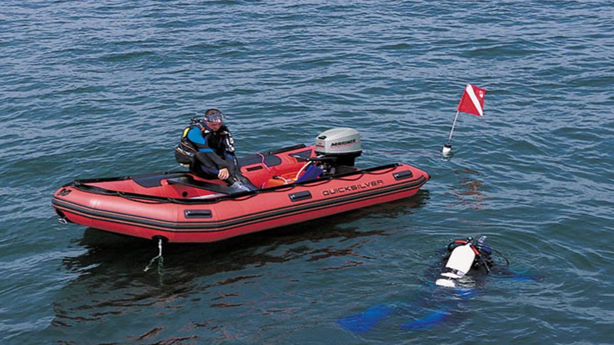 Diver surfacing beside an inflatable boat with a dive flag